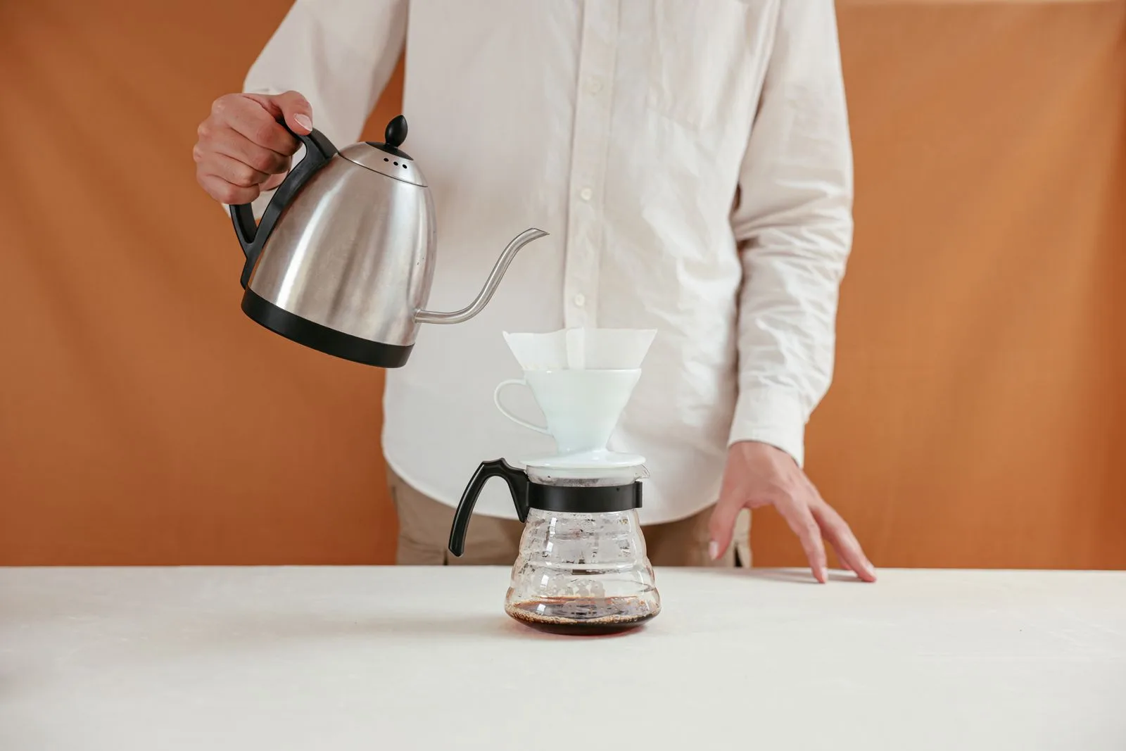 Pouring hot water in measured stages over coffee grounds during brewing