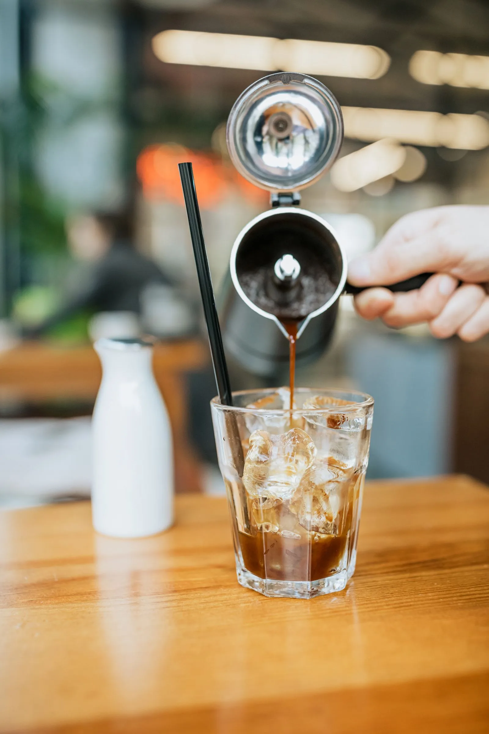 Pouring cold brew coffee over ice into a tall glass