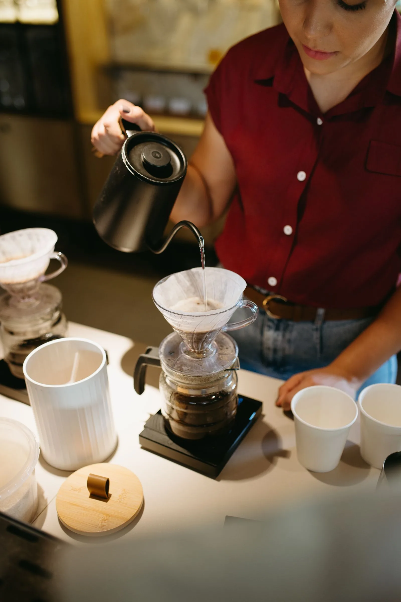 Barista pouring brewed coffee into a cup at a busy cafe counter