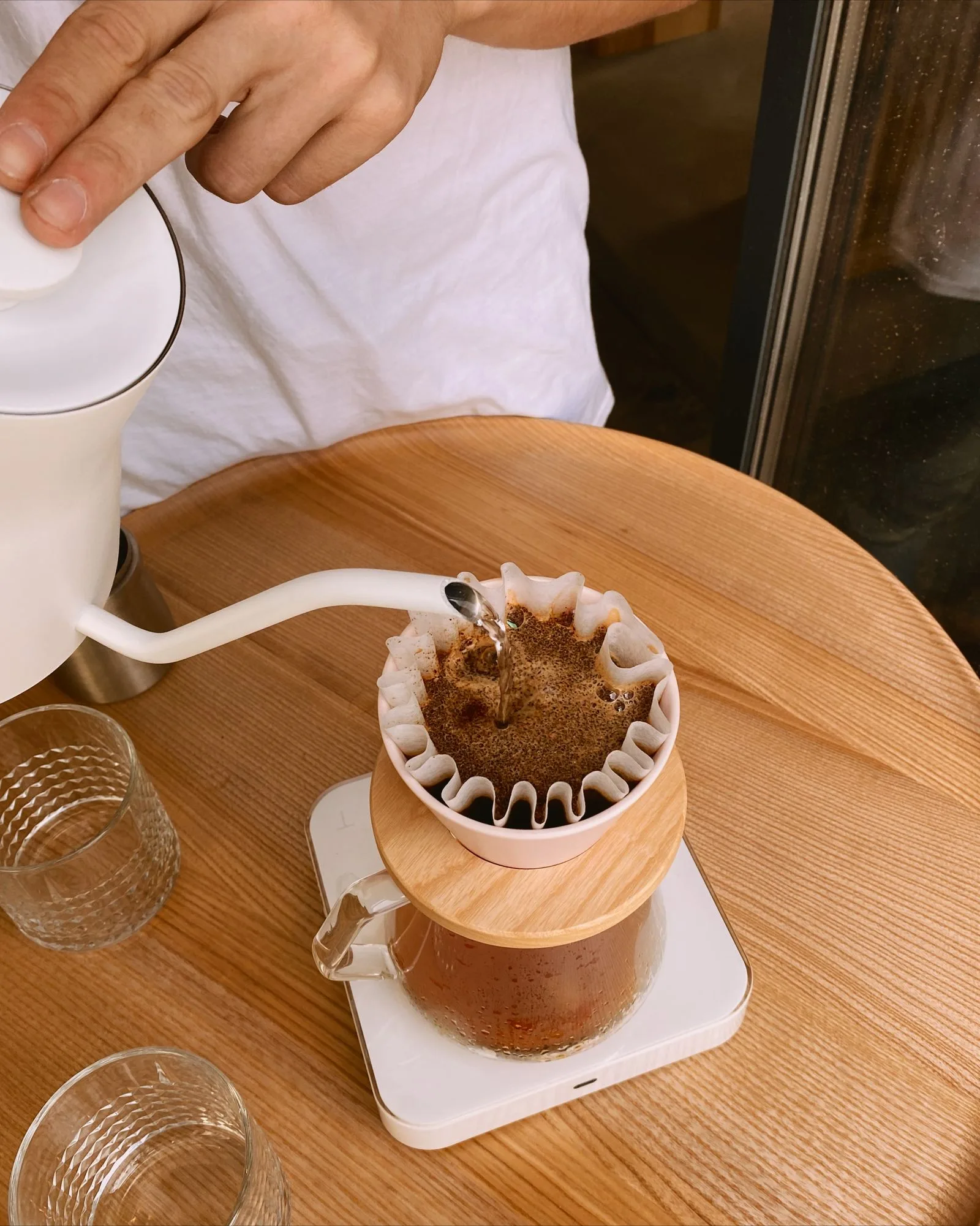 Coffee being poured from a brewing pot into a cup, showing fresh batch brewing