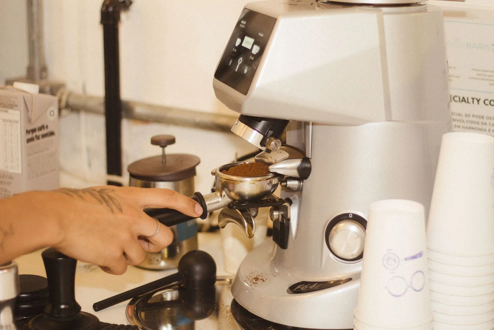 Barista's hand adjusting the grind size dial on a espresso grinder