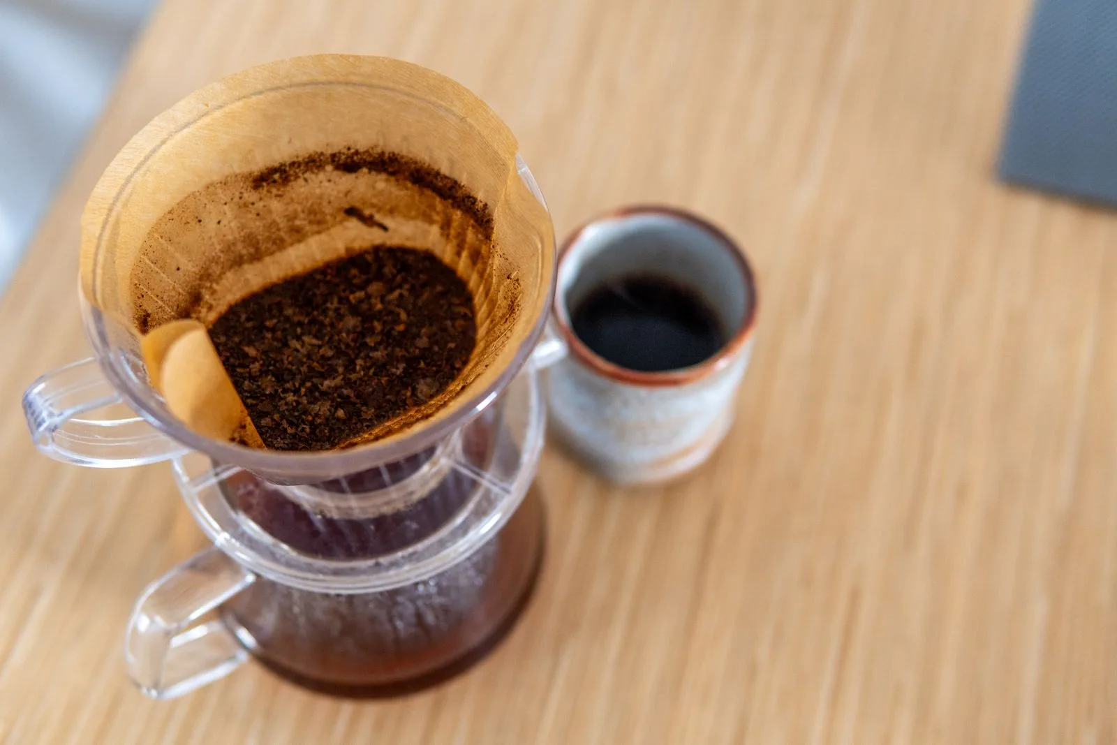 Brewed coffee being poured into different-sized ceramic cups