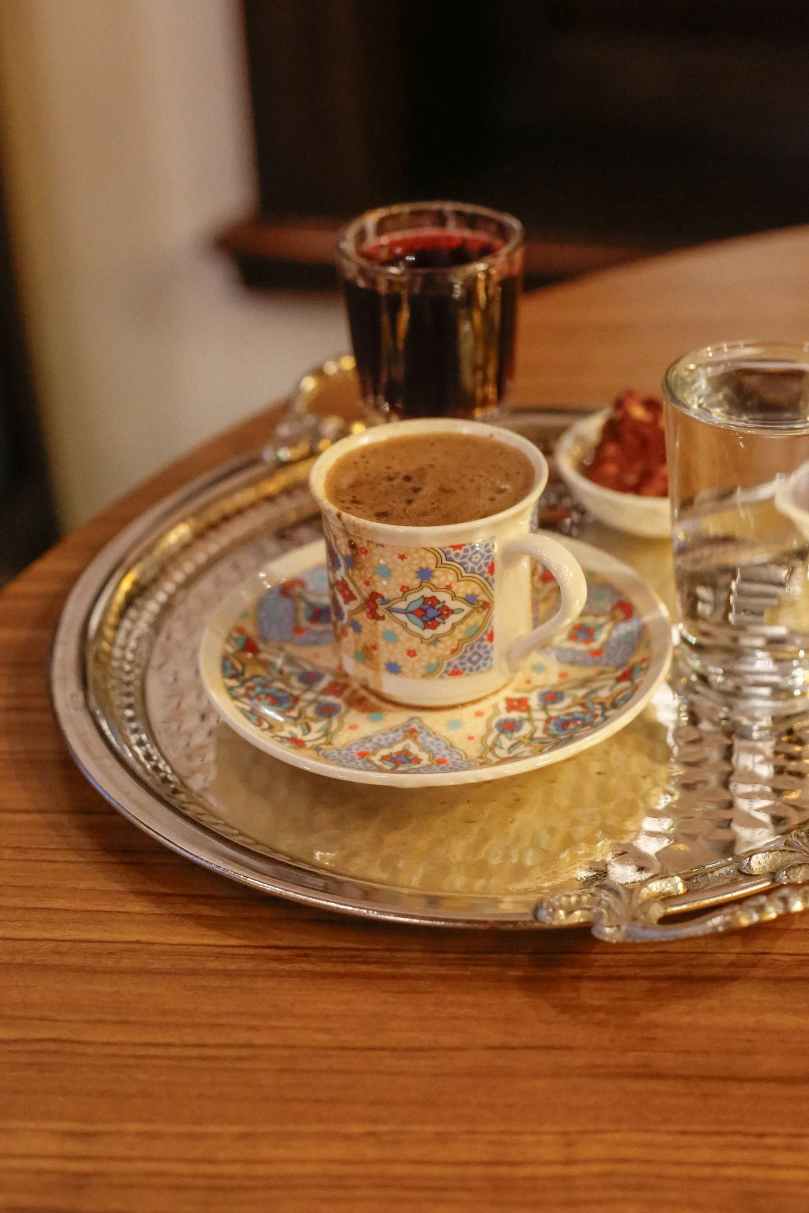 Turkish coffee in small traditional cups with foam and a glass of water on a decorative tray