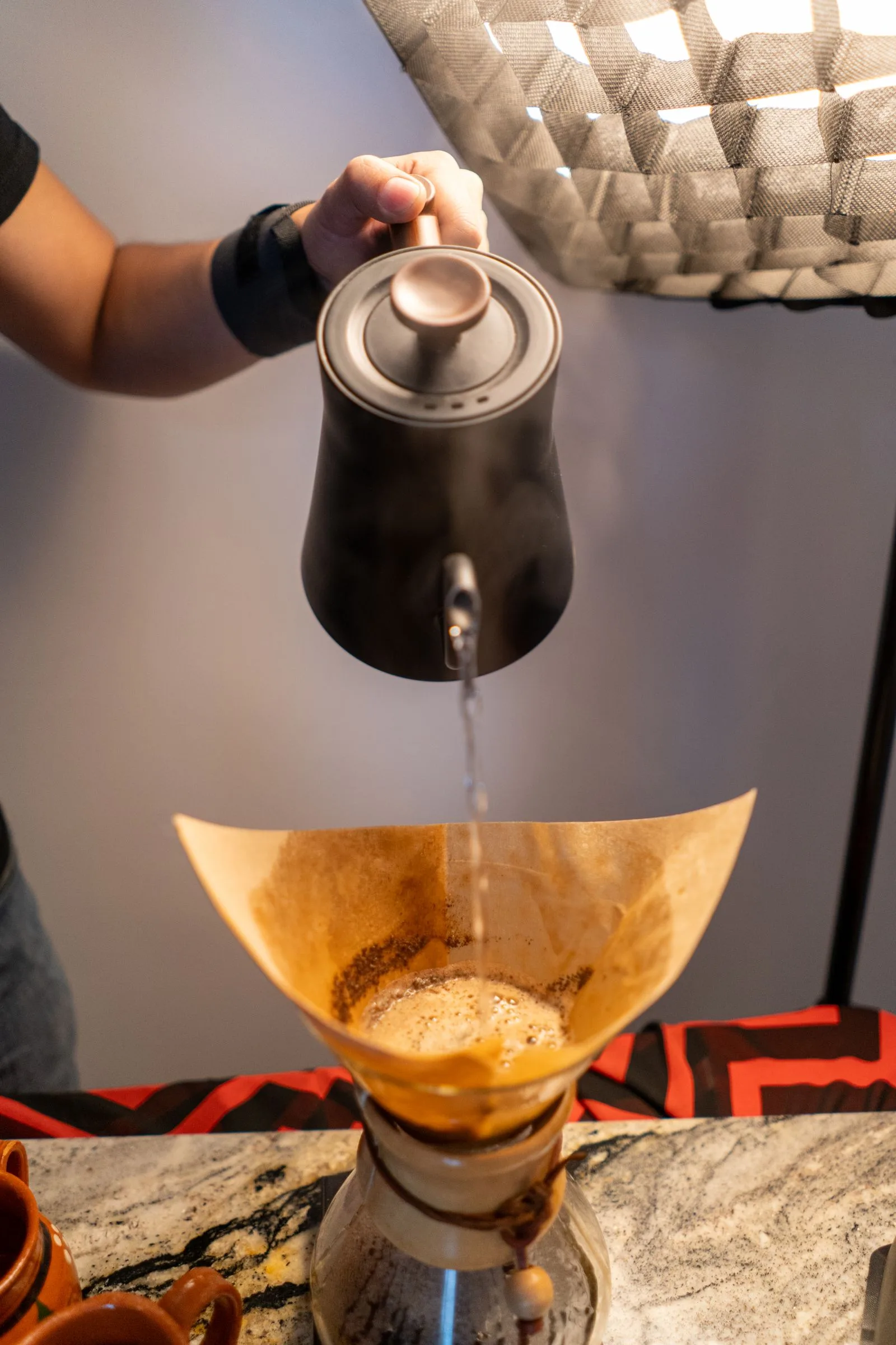 Stream of hot water from a kettle pouring into coffee filter basket